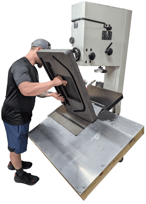 Worker guiding a foam lid insert through a vertical cutting machine.