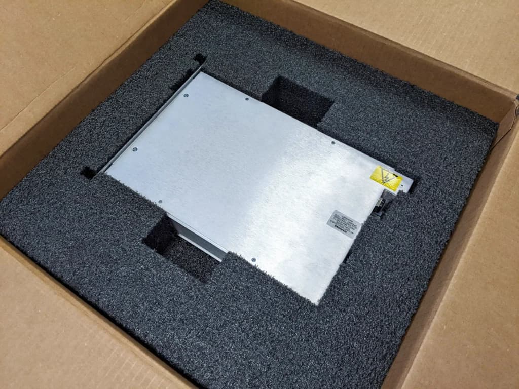 Metal equipment housing supported by shaped foam inside a cardboard box