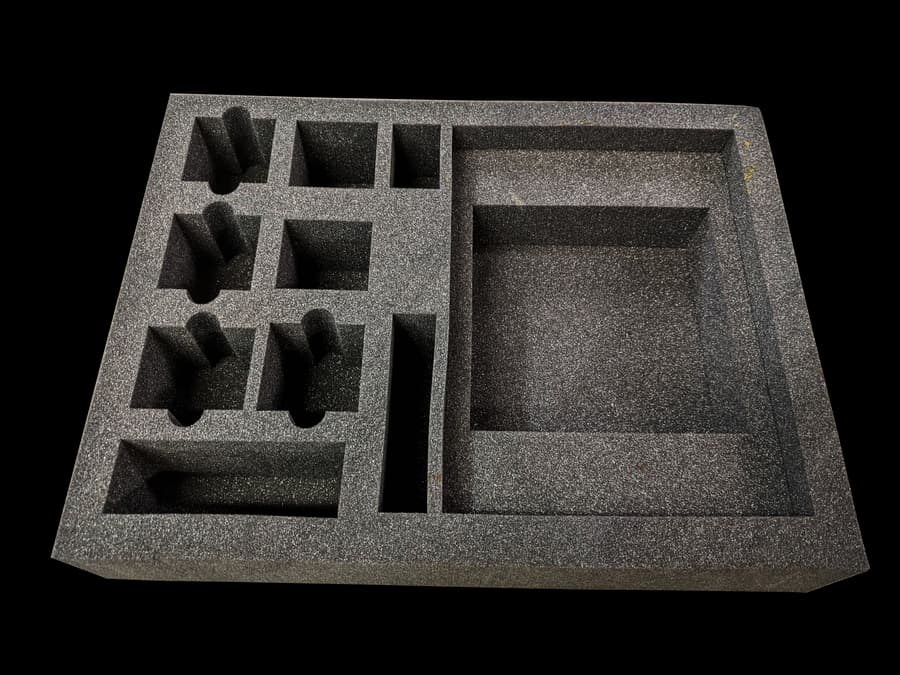 Dark foam insert with shaped pockets and rectangular compartments.
