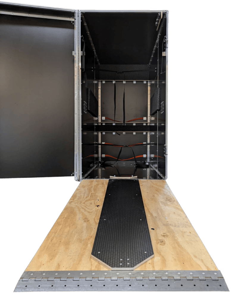 Upright black case with an open door, internal restraints and a lowered wooden ramp.