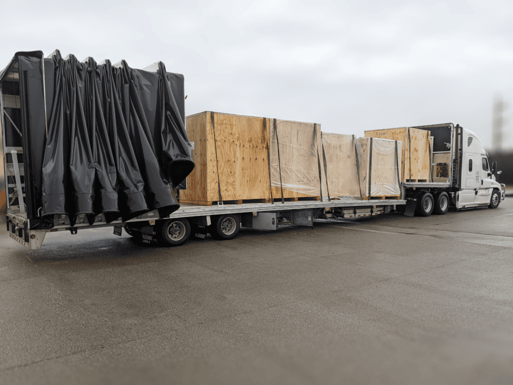 Several large wood crates secured on a curtain-sided truck trailer