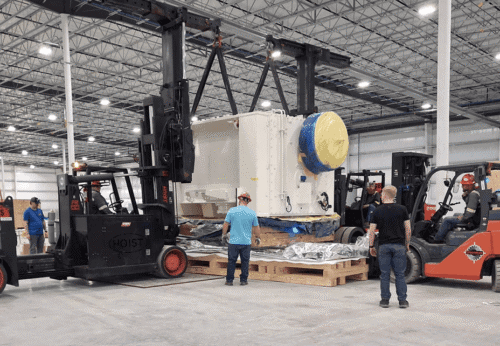 Forklifts setting large equipment onto a crate